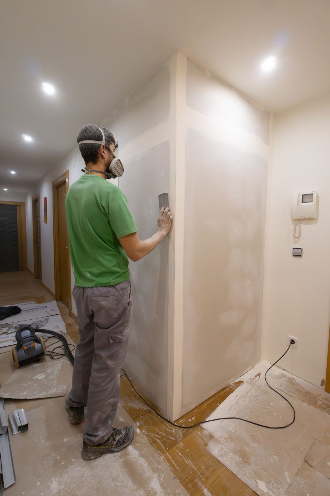 Sanding drywall in a hallway remodel